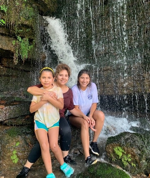 Marcela, her mother and sister sitting under a waterfall in Rock Island State Park, Tennessee.